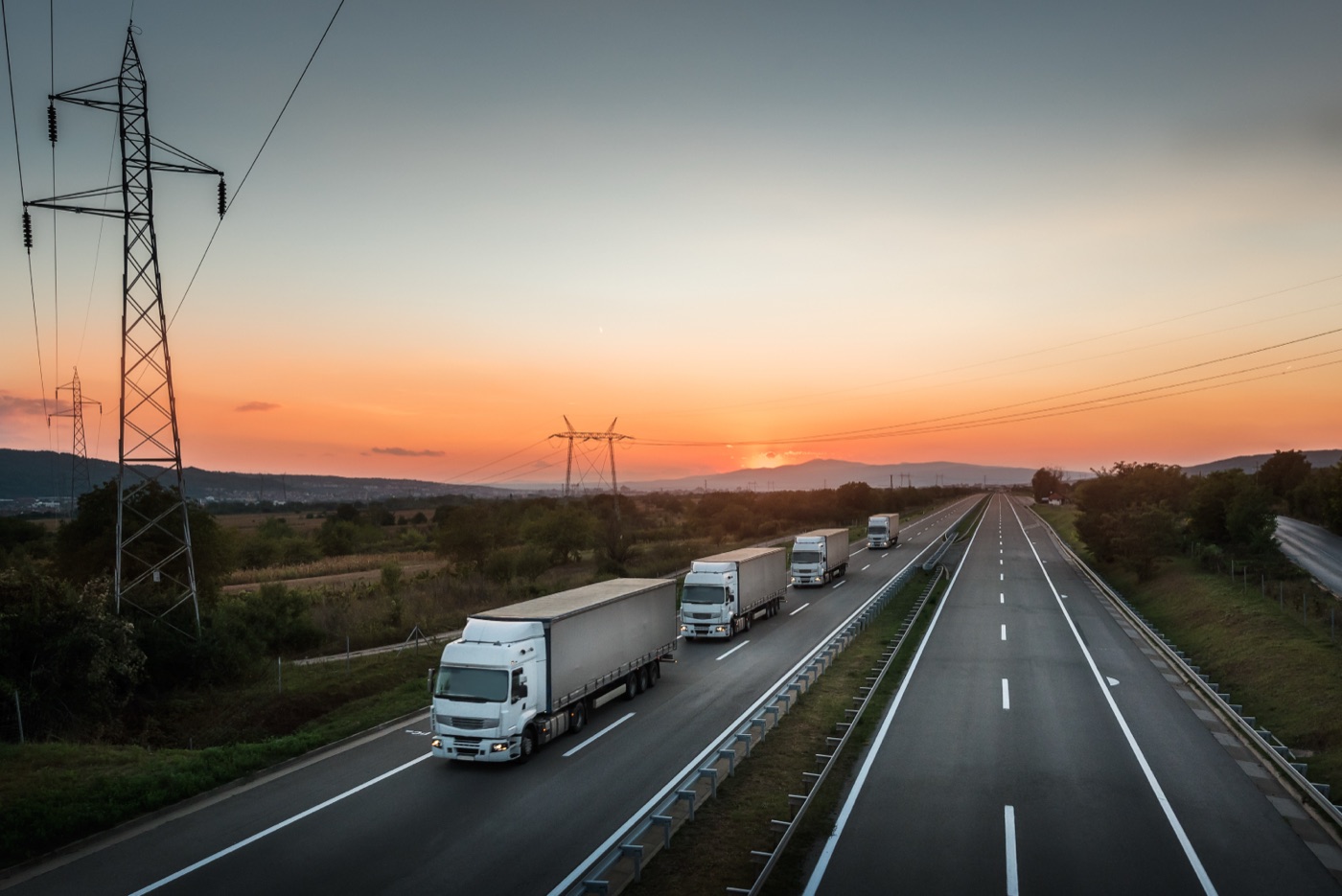 Trucks in convoy on a motorway at sunset